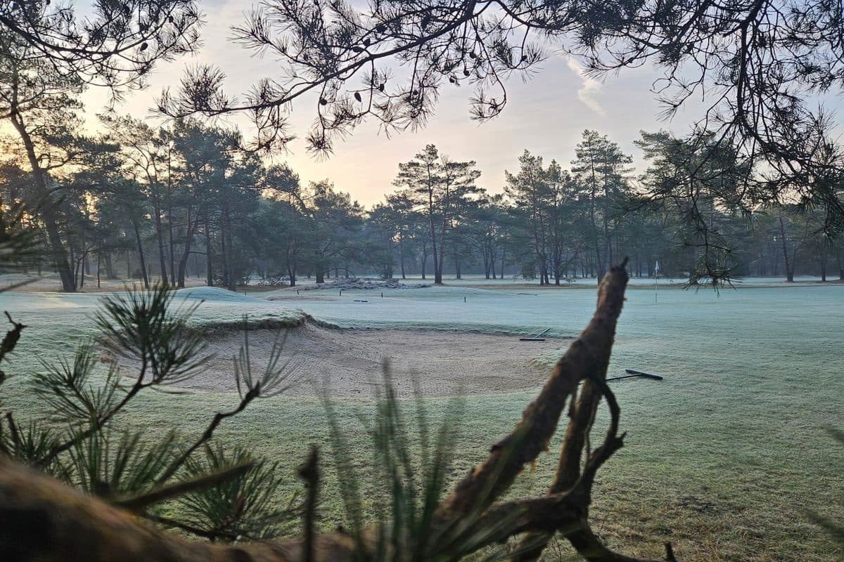 Golfer teeing off on a frosty UK parkland course in winter